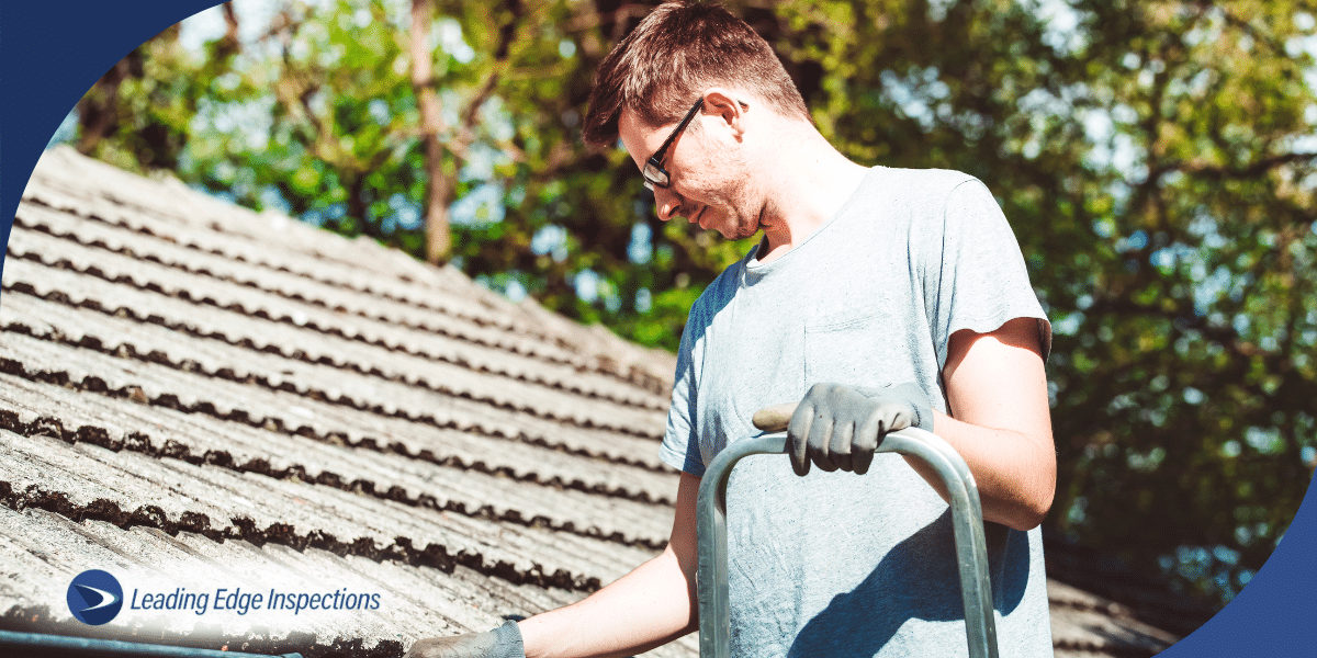 A person inspecting the roof while standing on a ladder.