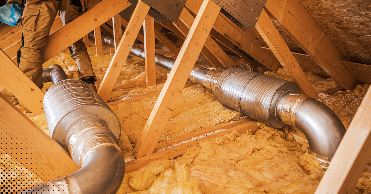 HVAC ductwork installed in attic with insulation.