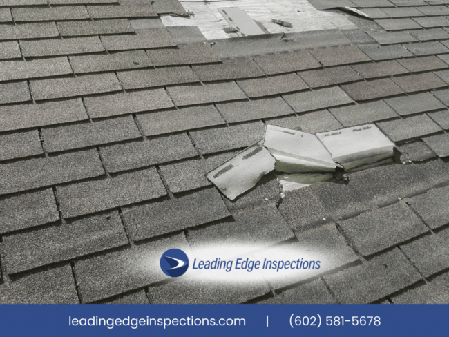 Damaged roof shingles with exposed flashing indicating potential leak risk.