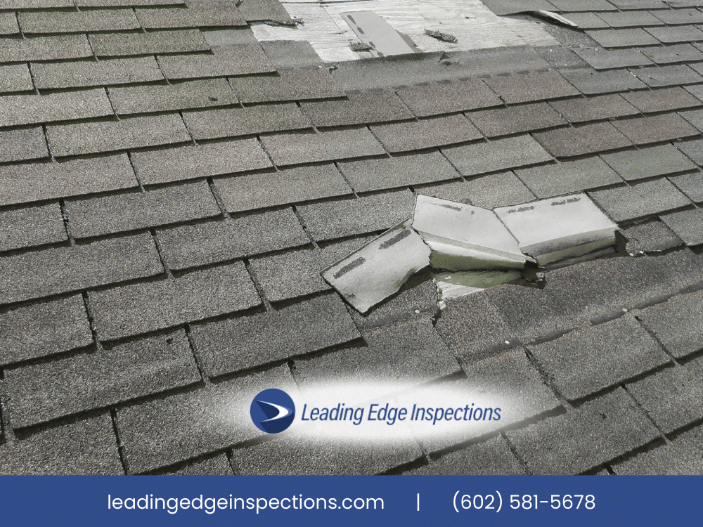 Damaged roof shingles with exposed flashing indicating potential leak risk.