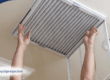 Hands replacing home HVAC air filter.